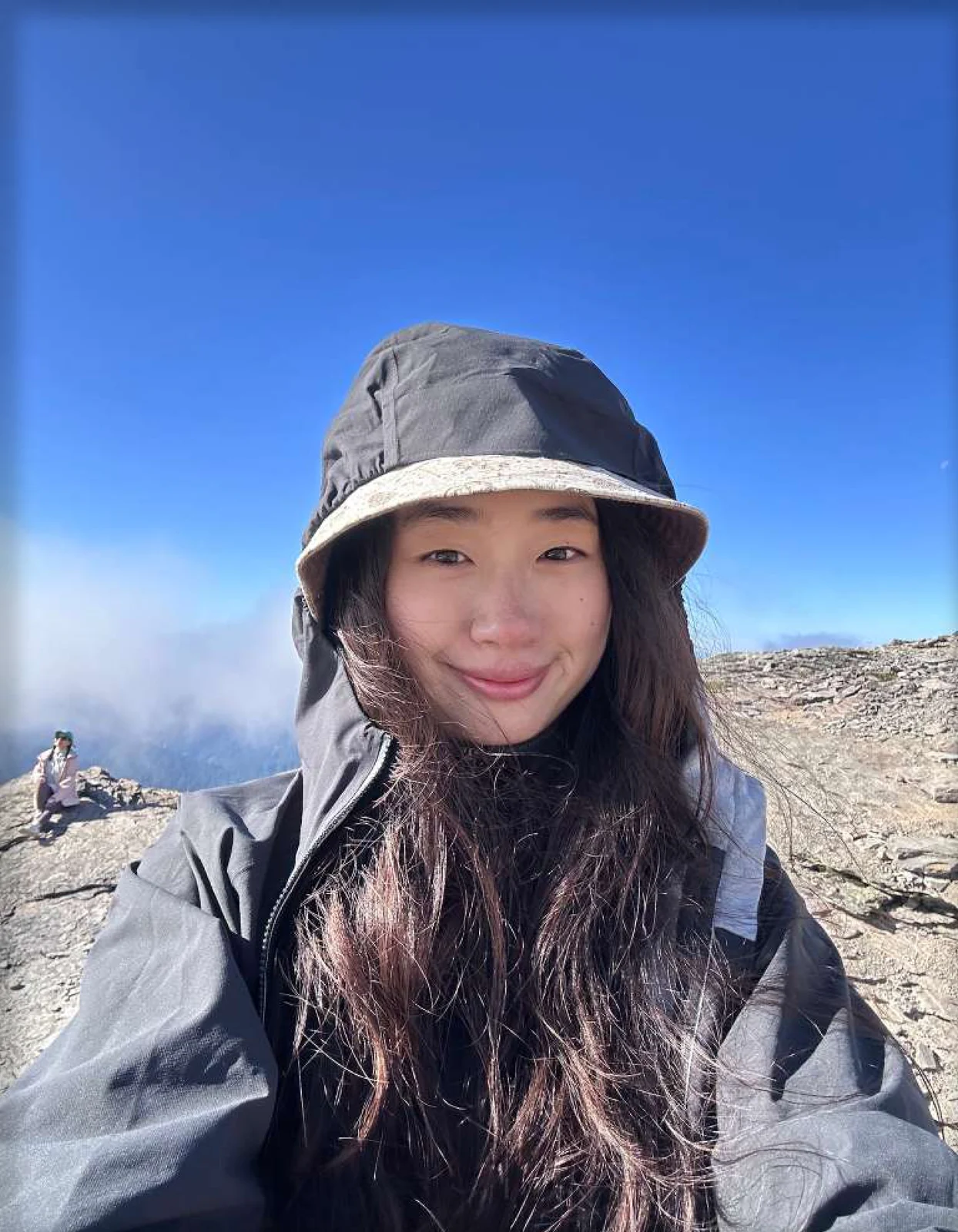 Freya smiling on a mountain beneath a vivid blue sky.